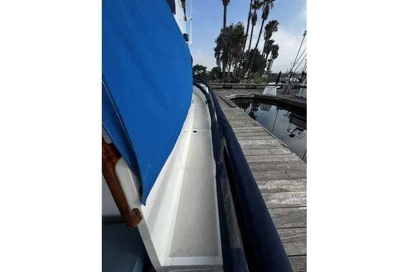 Slide: The Image of 1974 Grand Banks 32 Sedan boat docked, featuring blue cover and wooden deck. - 3