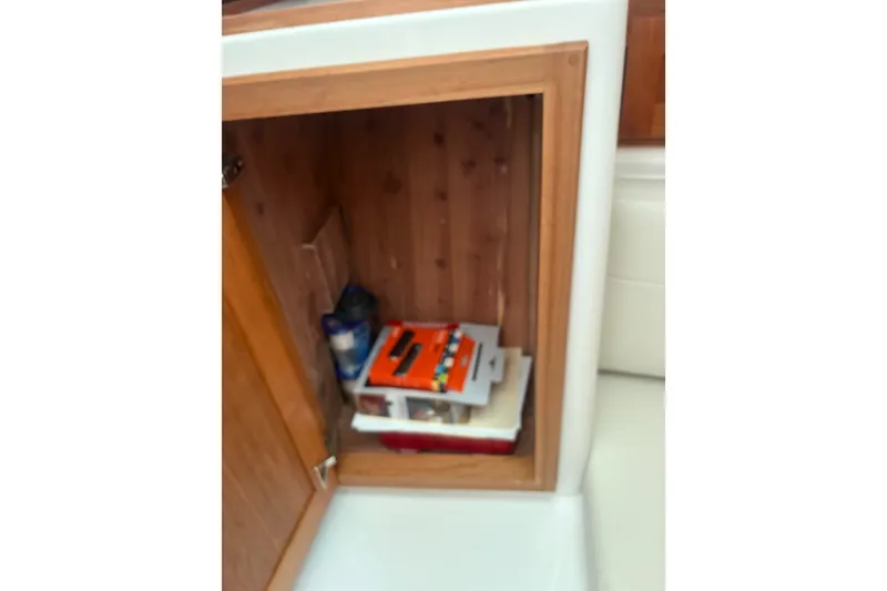 Slide: The Image of Open wooden cabinet on Back Cove 39O boat, showing stored items inside. - 11