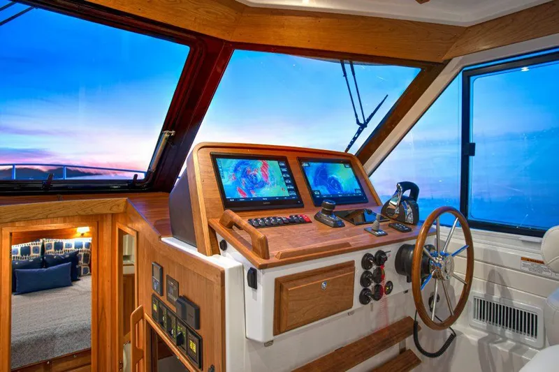 Slide: The Image of Manufacturer Provided Image: 2025 Back Cove 39O helm with navigation screens, wooden accents, and ocean view at sunset. - 52