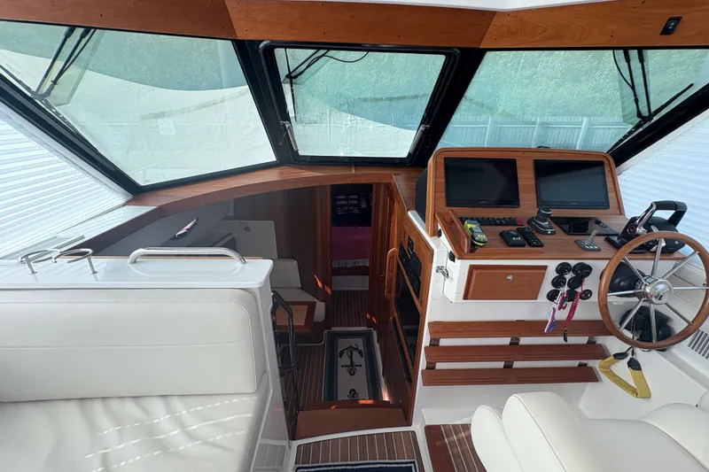 Slide: The Image of 2025 Back Cove 39O helm with modern controls, wooden accents, and comfortable seating. - 21
