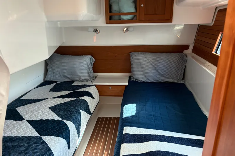 Slide: The Image of 2025 Back Cove 39O cabin interior with twin beds and wooden accents. - 18