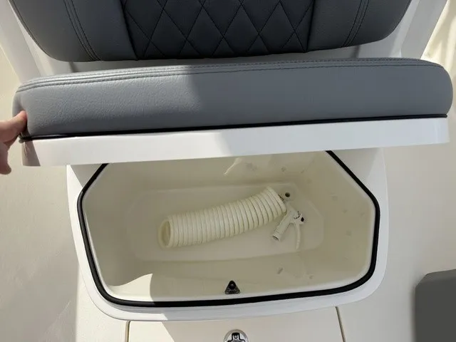 Slide: The Image of A storage compartment with a white hose inside, beneath a cushioned seat. - 28