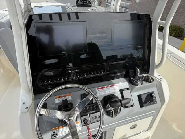 Slide: The Image of The image shows the cockpit of a 2024 Cobia 280 Center Console boat with modern instruments. - 19