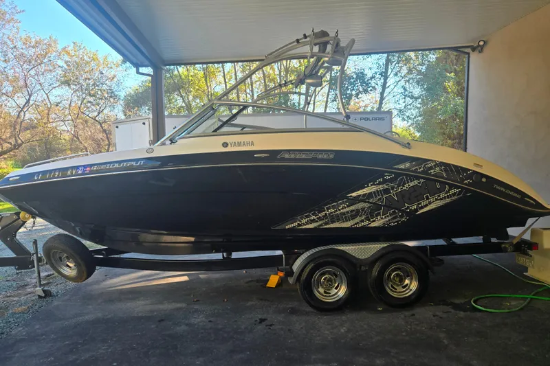 The Image of 2013 Yamaha Boats AR240 HO on trailer under a canopy, side view. - 0