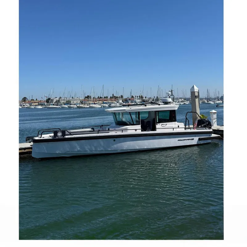 The Image of 2021 Axopar 28 Cabin BRABUS Trim Wet Bar docked in a marina under clear blue skies. - 0