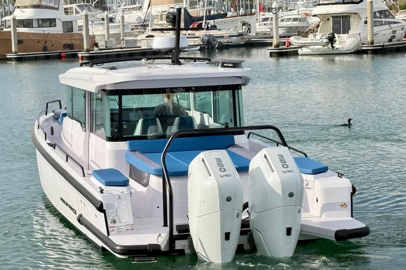 Slide: The Image of 2025 Axopar 37 XC Cross Cabin boat docked in a marina with twin engines. - 4