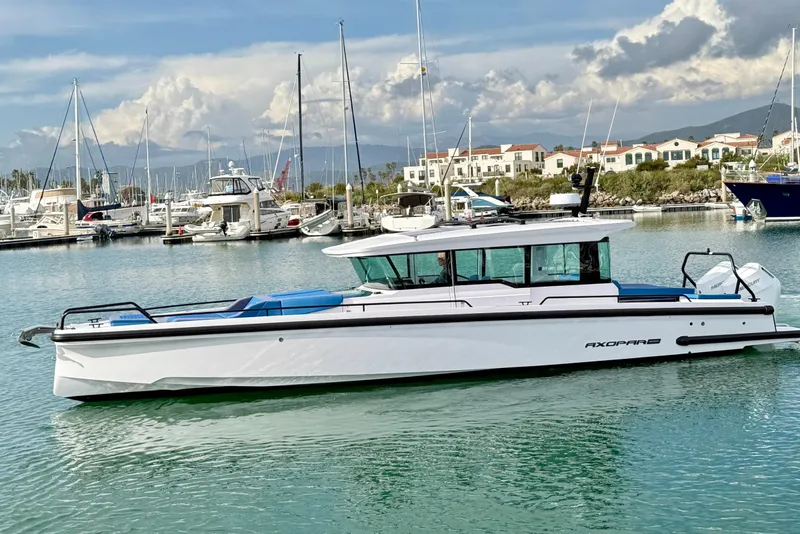Slide: The Image of 2025 Axopar 37 XC Cross Cabin boat docked in a marina with scenic background. - 7