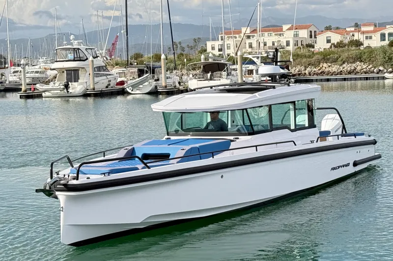 Slide: The Image of 2025 Axopar 37 XC Cross Cabin boat docked in a marina with scenic background. - 9