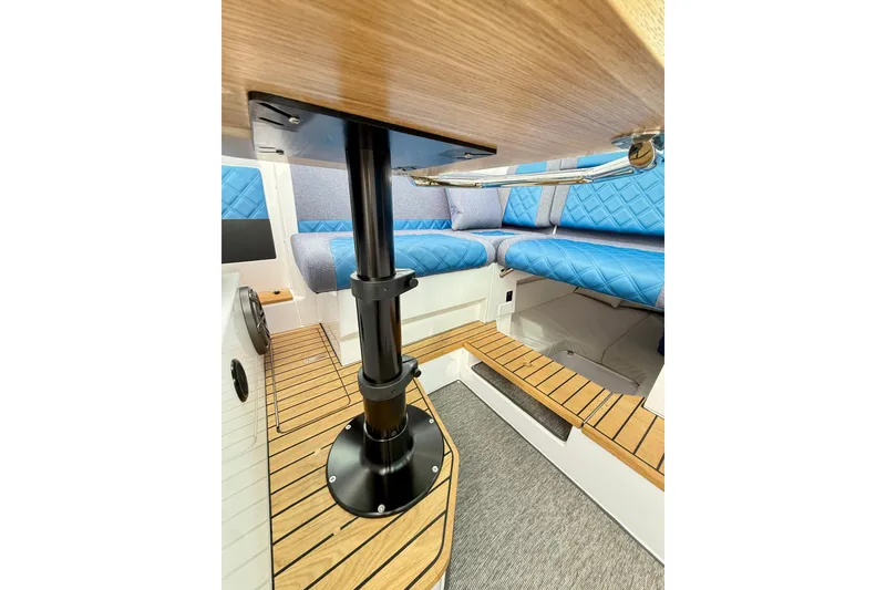 Slide: The Image of 2025 Axopar 37 XC Cross Cabin interior with blue seating and wood flooring. - 15