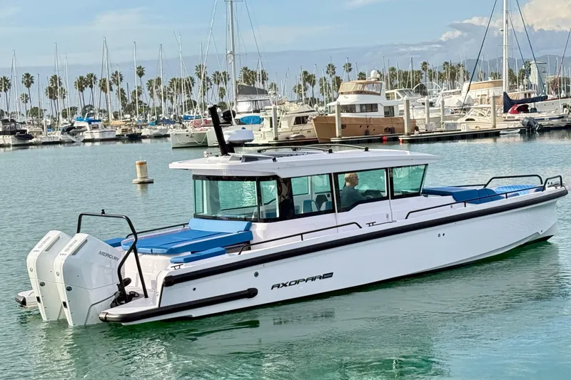 Slide: The Image of 2025 Axopar 37 XC Cross Cabin boat docked in a marina with palm trees. - 1
