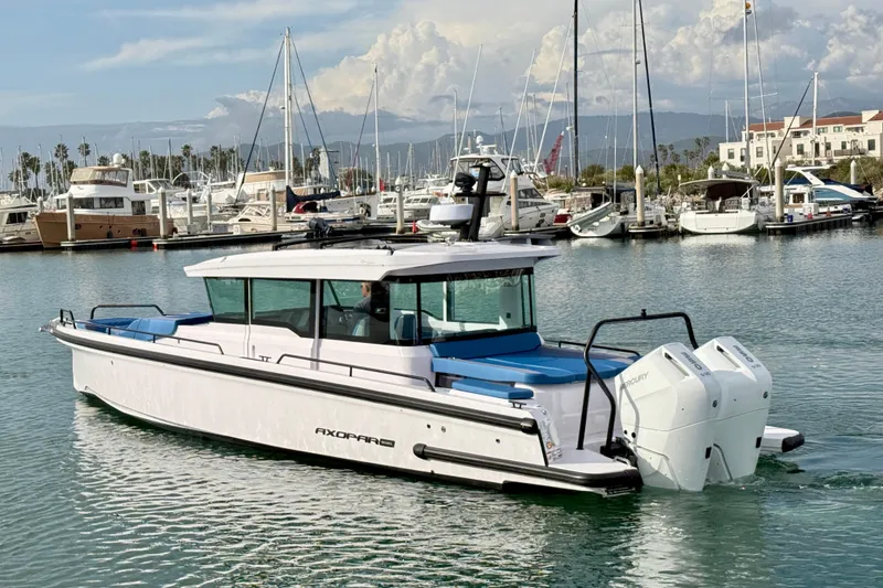 Slide: The Image of 2025 Axopar 37 XC Cross Cabin boat in marina, featuring twin outboard engines. - 5