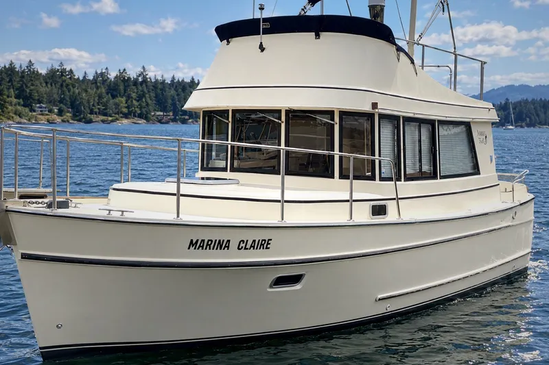 Slide: The Image of 2005 Camano 31 Troll boat named "Marina Claire" on a scenic waterway. - 2