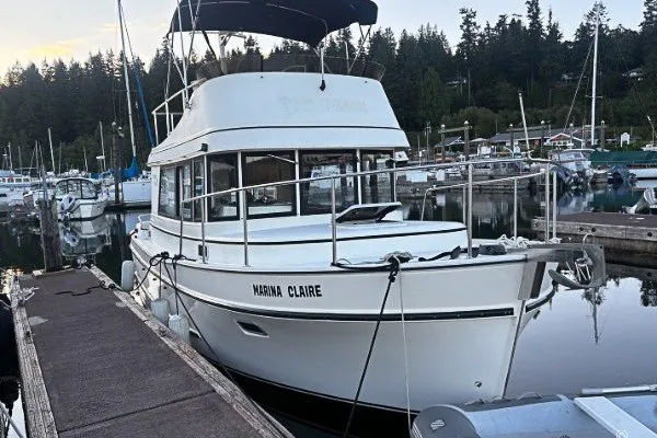 Slide: The Image of 2005 Camano 31 Troll boat docked in a marina, surrounded by trees and other boats. - 1