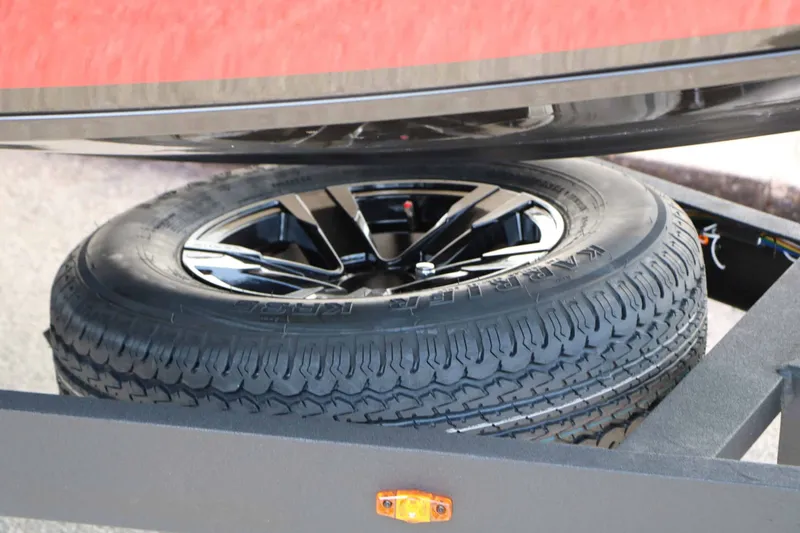 Slide: The Image of A spare tire with a black rim is mounted under a red boat. - 23