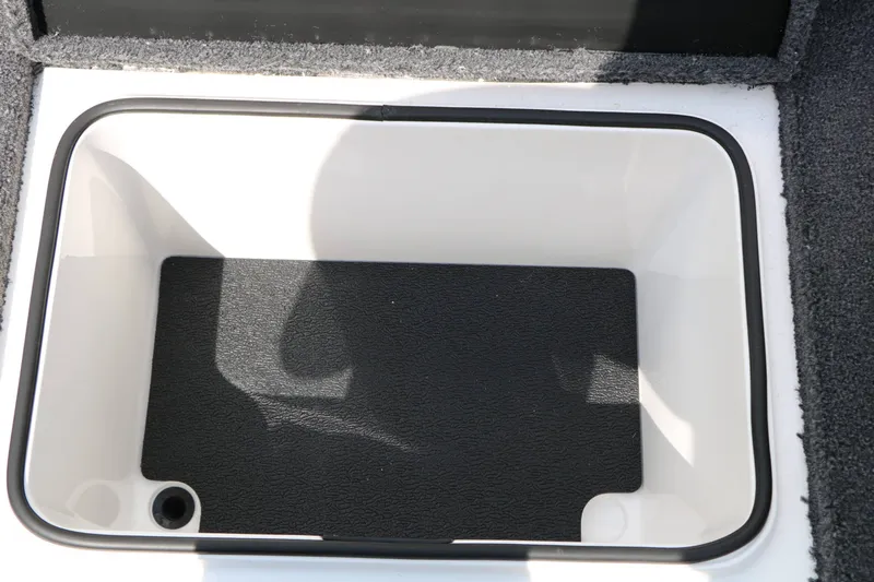 Slide: The Image of An open storage compartment with a black floor and white rim on a boat. - 48