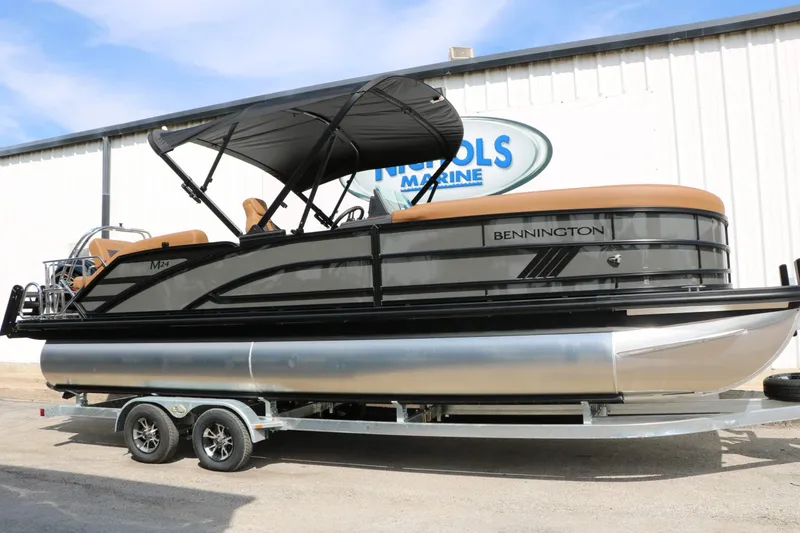 Slide: The Image of A 2027 Bennington 24 MSL Tri Toon on a trailer, featuring a black canopy and brown seating. - 3