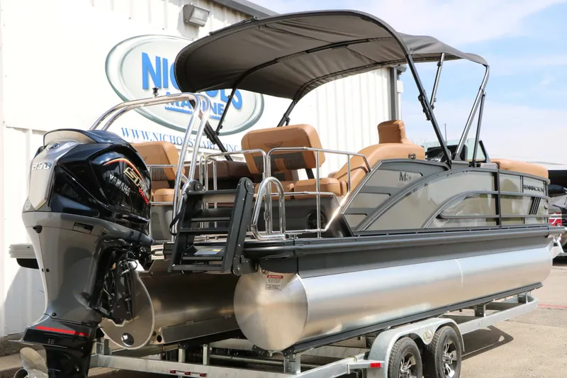Slide: The Image of A 2027 Bennington 24 MSL Tri Toon on a trailer. It features a black canopy and an outboard motor. - 15