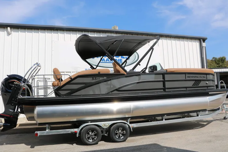 Slide: The Image of A sleek 2027 Bennington 24 MSL Tri Toon on a trailer, featuring a black canopy. - 13
