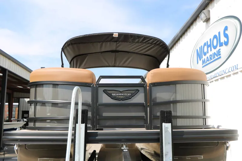 Slide: The Image of A 2027 Bennington 24 MSL Tri Toon on a trailer in front of a building with a "Nichols Marine" sign. - 8