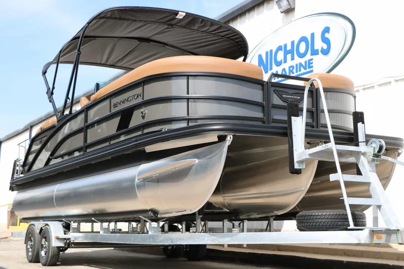 Slide: The Image of A 2027 Bennington 24 MSL Tri Toon on a trailer, featuring black railings and a sunshade. - 7