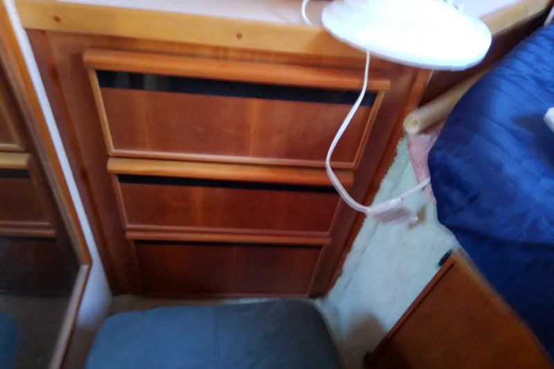 Slide: The Image of Interior of 1989 Sea Ray 440 Aft Cabin with wooden drawers and blue bedding. - 42