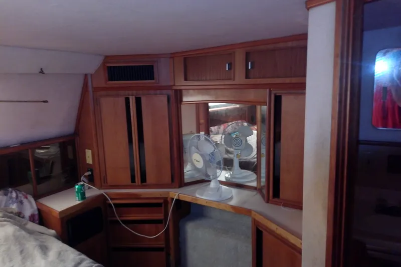 Slide: The Image of 1989 Sea Ray 440 Aft Cabin interior with wooden cabinetry and a fan. - 54