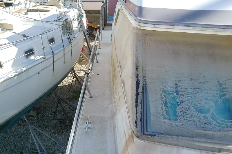 Slide: The Image of 1989 Sea Ray 440 Aft Cabin yacht on dry dock, showing weathered exterior and window. - 23