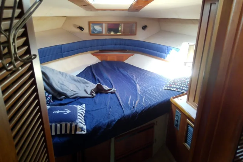 Slide: The Image of 1989 Sea Ray 440 Aft Cabin bedroom with blue bedding and nautical decor. - 35