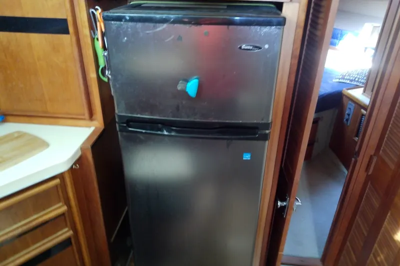 Slide: The Image of 1989 Sea Ray 440 Aft Cabin interior with stainless steel refrigerator in kitchen area. - 32