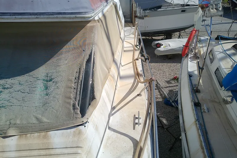 Slide: The Image of 1989 Sea Ray 440 Aft Cabin boat with weathered exterior, docked alongside other vessels. - 22