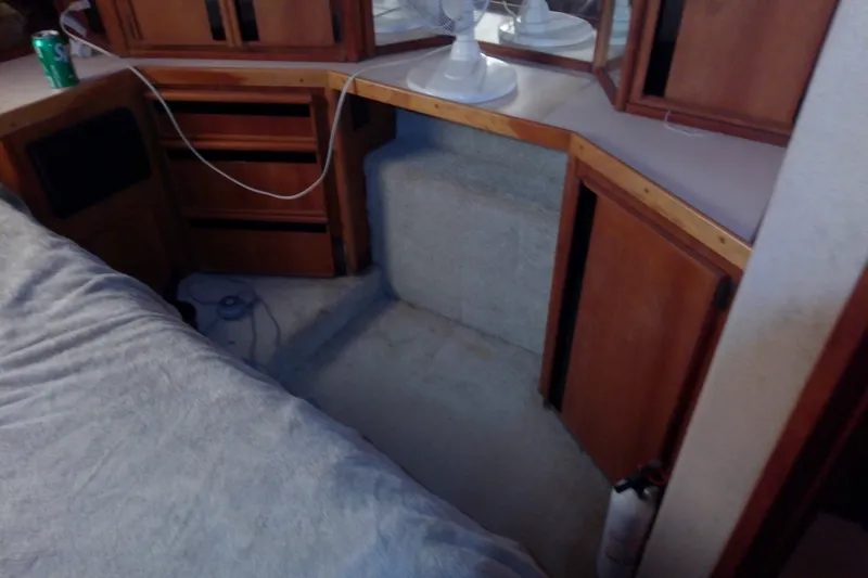 Slide: The Image of 1989 Sea Ray 440 Aft Cabin interior with wooden cabinets and a small fan. - 55
