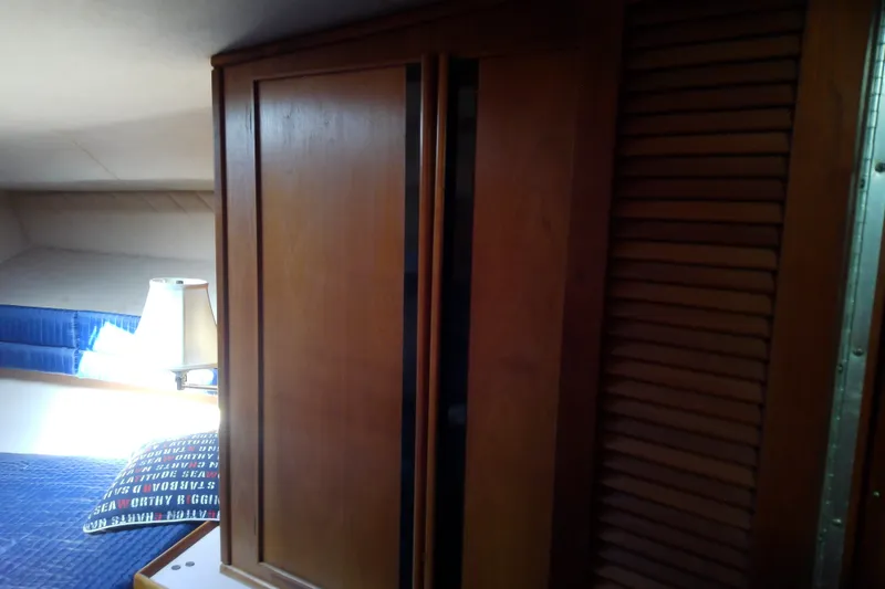Slide: The Image of Interior of 1989 Sea Ray 440 Aft Cabin with wooden cabinetry and cozy bedding. - 40