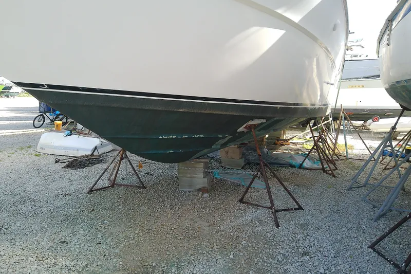 Slide: The Image of 1989 Sea Ray 440 Aft Cabin boat on stands, undergoing maintenance in a gravel yard. - 3