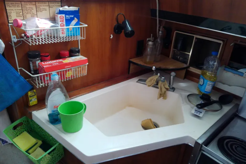 Slide: The Image of Kitchen sink area in a 1989 Sea Ray 440 Aft Cabin boat with cleaning supplies. - 31