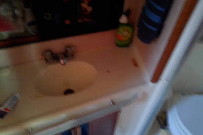 Slide: The Image of 1989 Sea Ray 440 Aft Cabin bathroom sink with toiletries and cleaning supplies. - 37