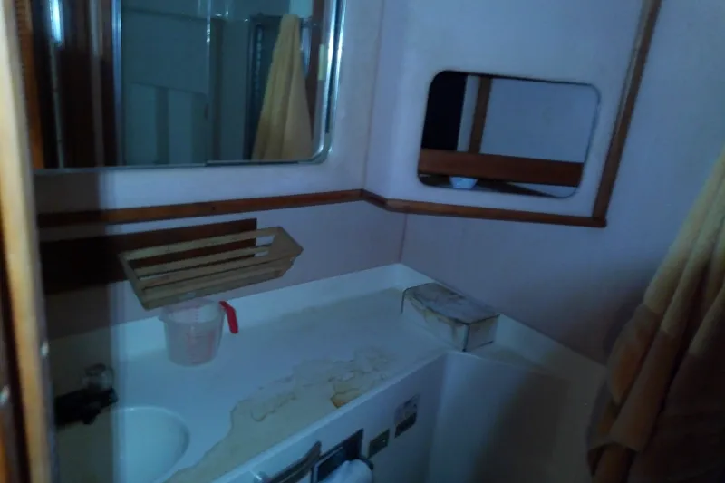 Slide: The Image of 1989 Sea Ray 440 Aft Cabin bathroom with sink, mirror, and wooden accents. - 52