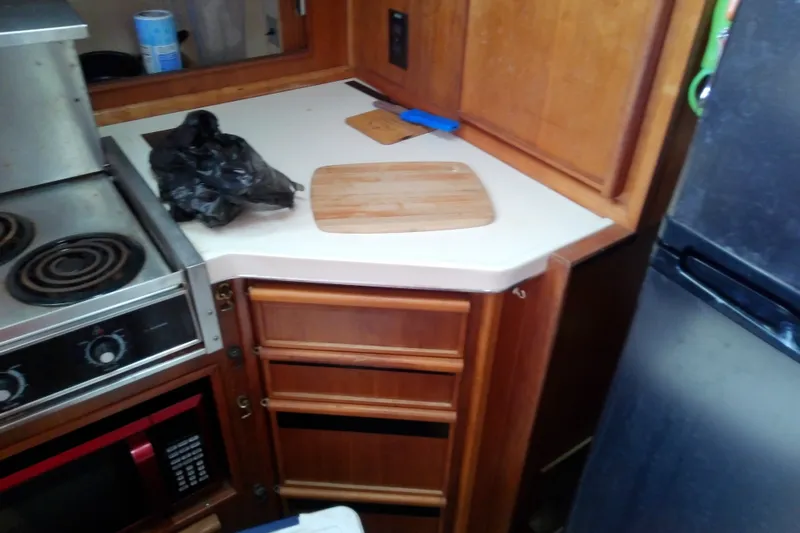 Slide: The Image of 1989 Sea Ray 440 Aft Cabin kitchen with stove, microwave, and wooden cabinets. - 30