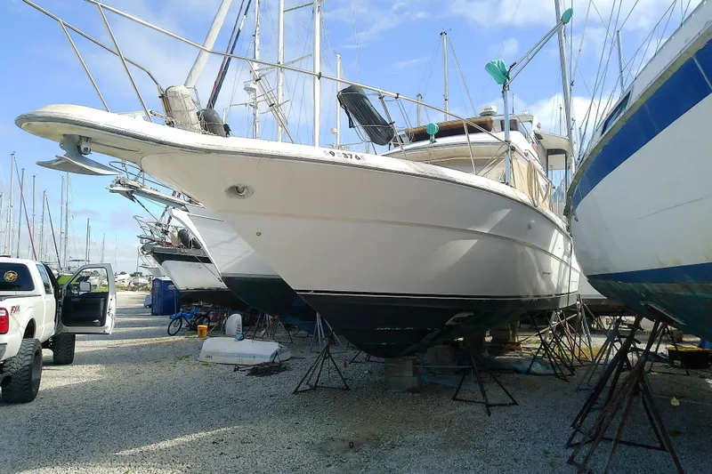 The Image of 1989 Sea Ray 440 Aft Cabin yacht on dry dock, surrounded by other boats. - 0