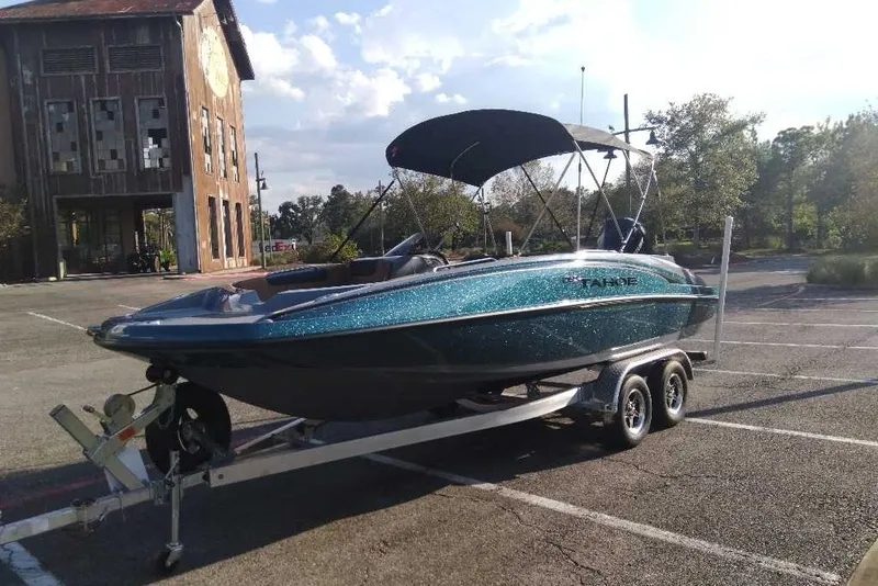 Slide: The Image of 2027 Tahoe 2150 boat on trailer in parking lot, rustic building background. - 6