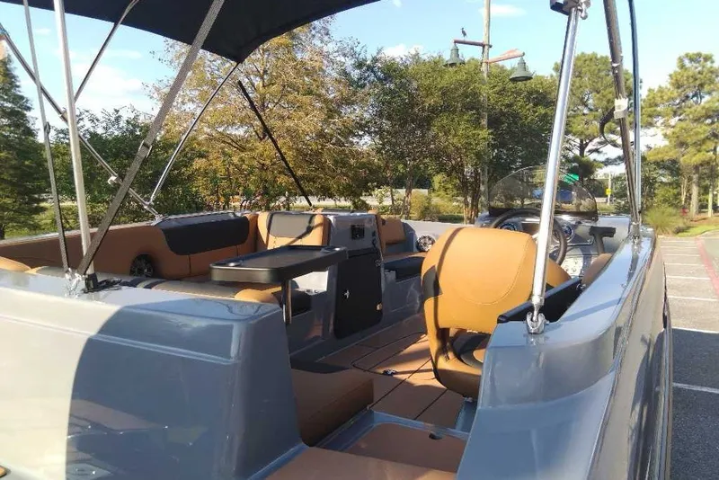 Slide: The Image of 2027 Tahoe 2150 boat interior with tan seating and canopy, parked outdoors. - 9