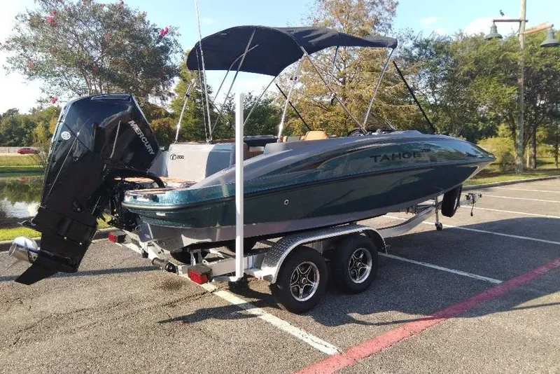 Slide: The Image of 2027 Tahoe 2150 boat on trailer with outboard motor, parked in sunny lot. - 2