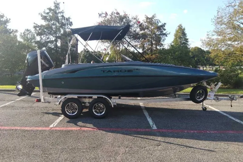 The Image of 2027 Tahoe 2150 boat on trailer in parking lot, surrounded by trees. - 0