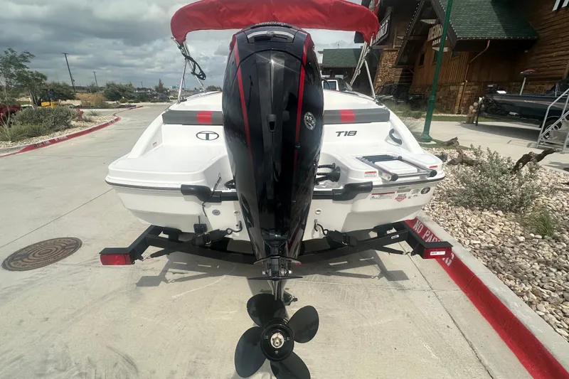 Slide: The Image of 2027 Tahoe T18 boat with outboard motor on trailer, parked outdoors. - 7