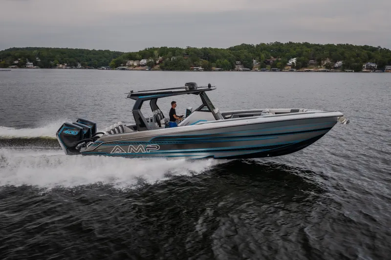 Slide: The Image of 2025 AMP 333 CC boat cruising on a lake with scenic shoreline background. - 8