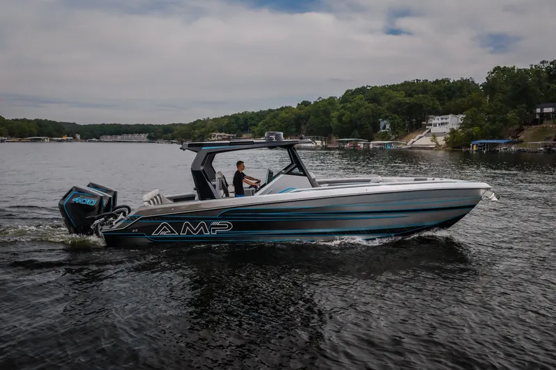 Slide: The Image of 2025 AMP 333 CC boat cruising on a scenic lake with lush green shoreline. - 3