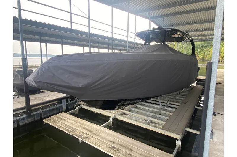 Slide: The Image of Covered AMP 333 CC boat, 2025 model, docked in a sheltered marina. - 12