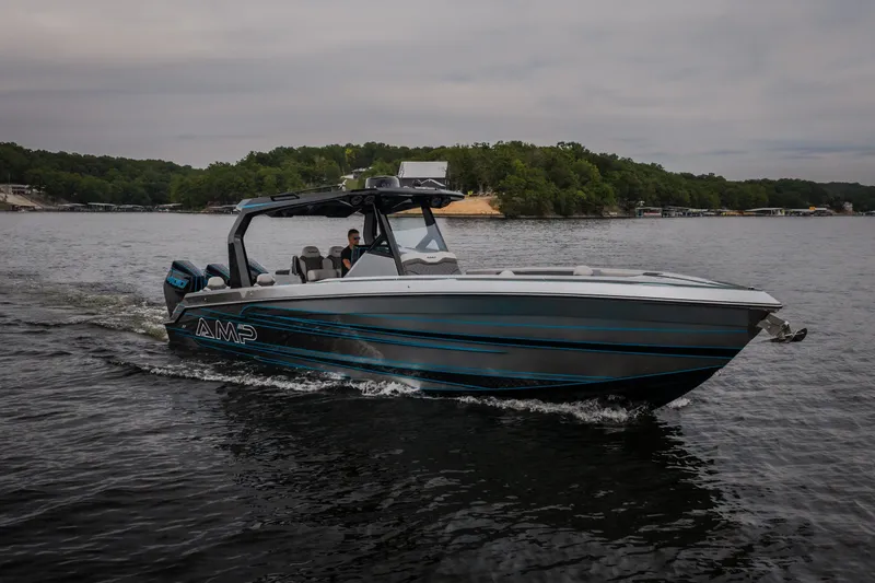 Slide: The Image of 2025 AMP 333 CC boat cruising on a lake with lush green shoreline. - 66