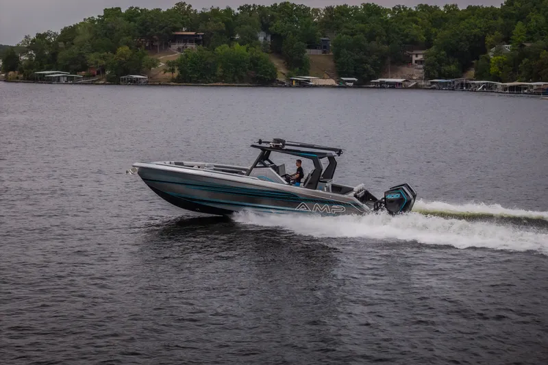 Slide: The Image of 2025 AMP 333 CC boat cruising on a lake with lush green shoreline. - 74
