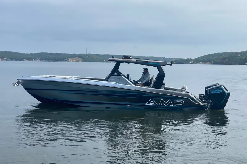 Slide: The Image of 2025 AMP 333 CC boat on calm water with scenic background. - 2