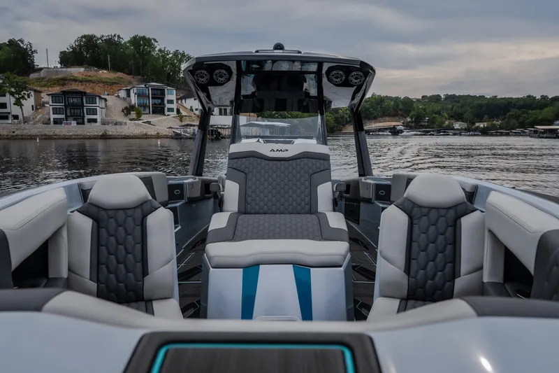 Slide: The Image of Luxury AMP 333 CC boat interior, 2025 model, on a scenic lake with modern homes. - 23